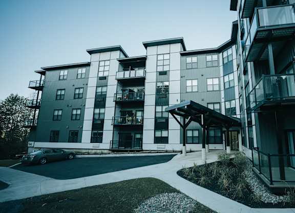 A modern apartment building with a car parked in front.