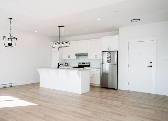 A kitchen with a white island and stainless steel appliances.