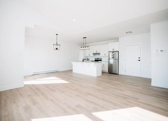 A kitchen with a refrigerator, sink, and cabinets.