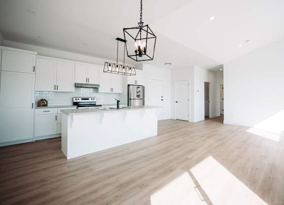 A modern kitchen with white cabinets and a wooden floor.