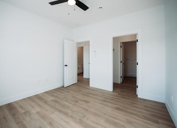 A room with a ceiling fan and wooden flooring.