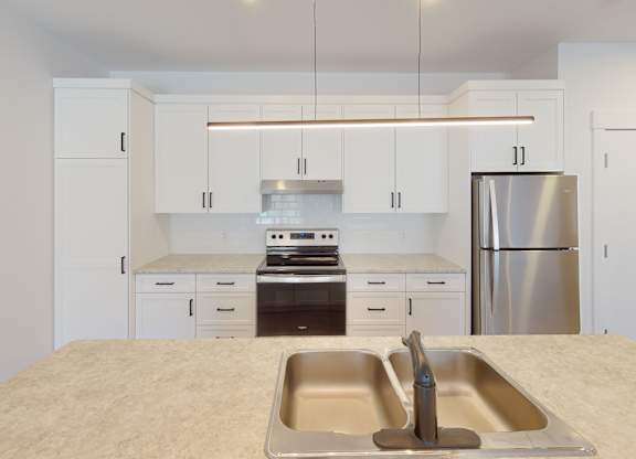 A kitchen with a sink, stove, and refrigerator.