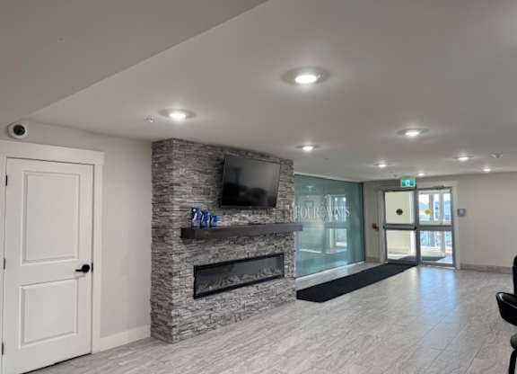 A living room with a stone fireplace and a flat screen TV mounted above it.