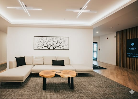 A modern living room with a white couch and a tree-like picture on the wall.