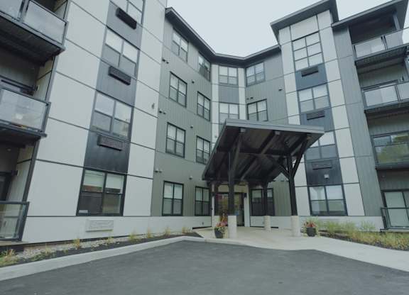 A modern building with a white and grey exterior and a black roof.