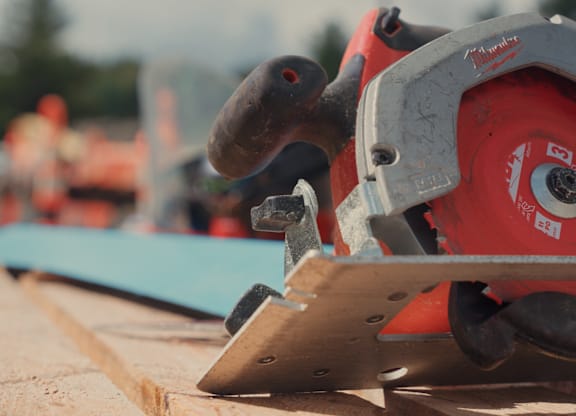 A circular saw is cutting a piece of wood.