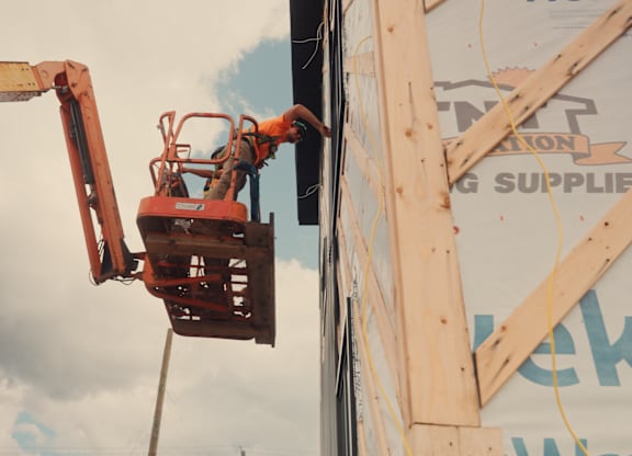 A man is working on a construction site with a cherry picker.