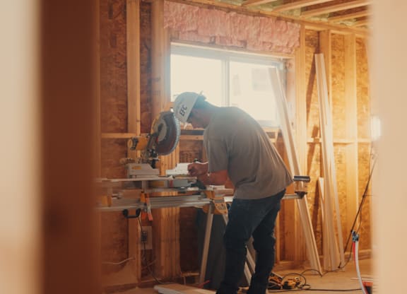 A man is cutting a piece of wood with a circular saw.