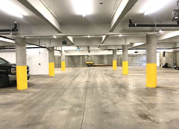 A parking garage with concrete floors and yellow poles.