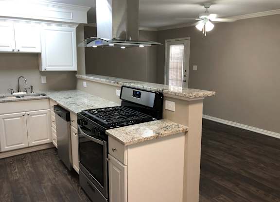 A kitchen with a black stove top oven and white cabinets.