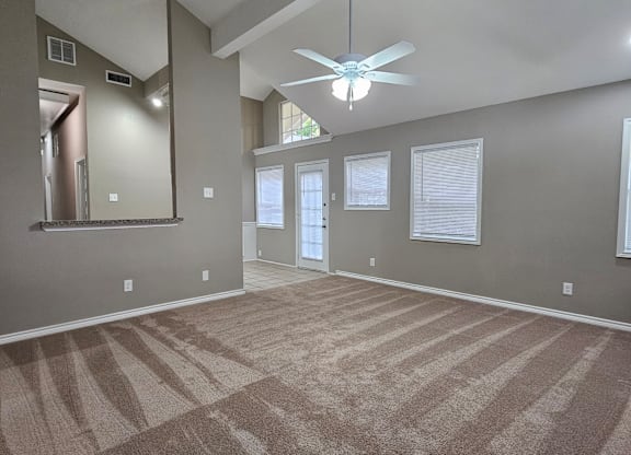 A room with a carpeted floor and a ceiling fan.