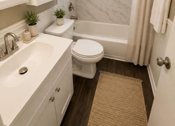 A white bathroom with a toilet, sink, and a window.