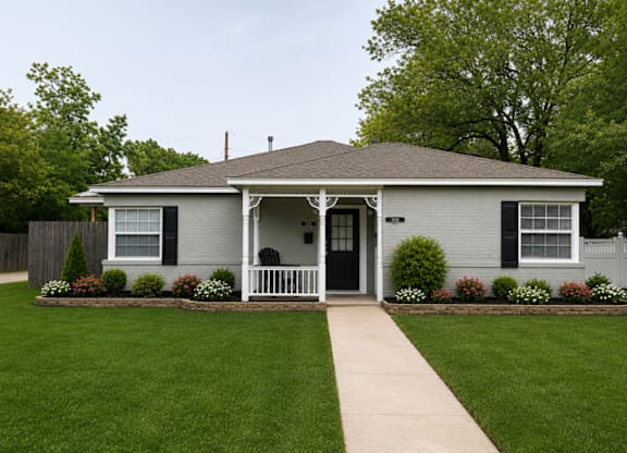 A small house with a front porch and a white picket fence.