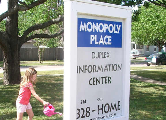 A girl watering flowers in front of a Monopoly Place sign.