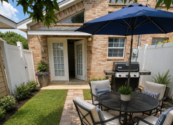 A patio with a table and chairs and an umbrella.