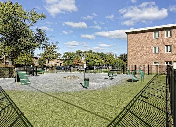 A dog park with a green slide and a brown building in the background.