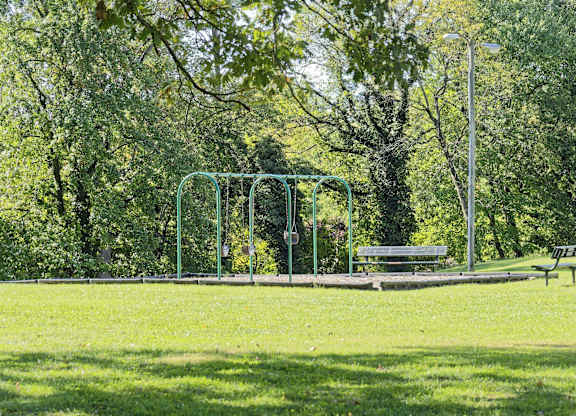 A park with a swing set and a bench.