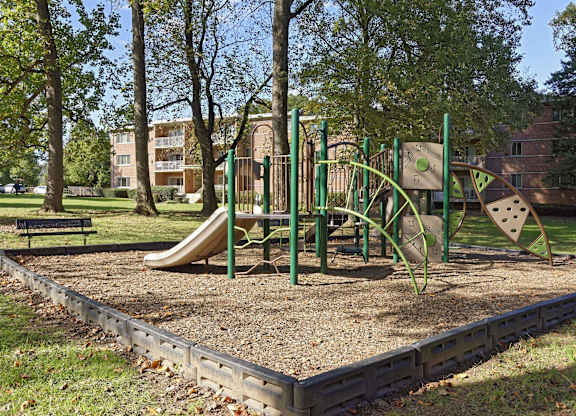 A playground with a slide, swings, and a seesaw.