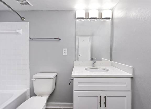 A white bathroom with a toilet, sink, and mirror.