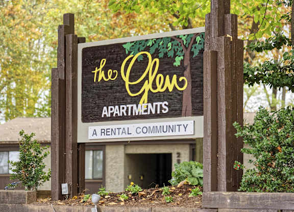 A sign for The Glen Apartments stands in front of a building.