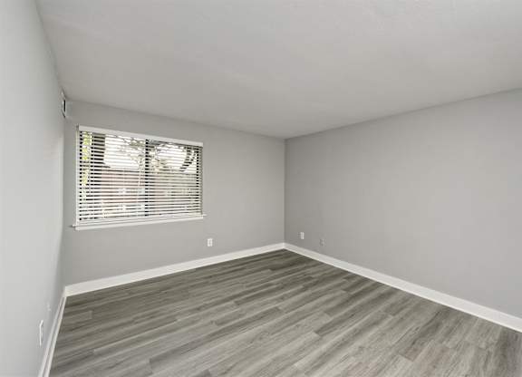 A room with a window and wooden flooring.