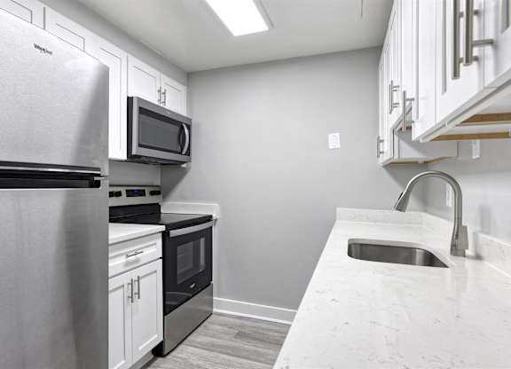 A kitchen with a stainless steel refrigerator, microwave, oven, and sink.