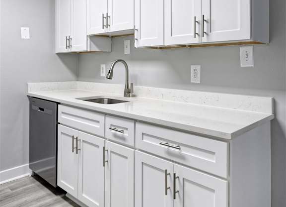 A kitchen with white cabinets and a white countertop.