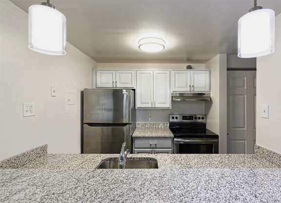 A kitchen with a granite counter top and stainless steel appliances.
