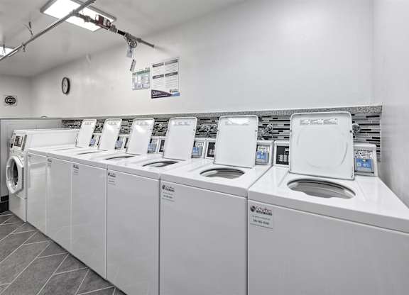 A row of white washing machines in a laundromat.