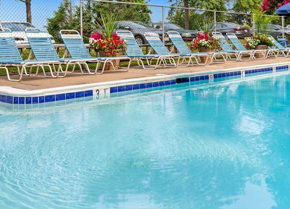 A pool with blue water and chairs around it.