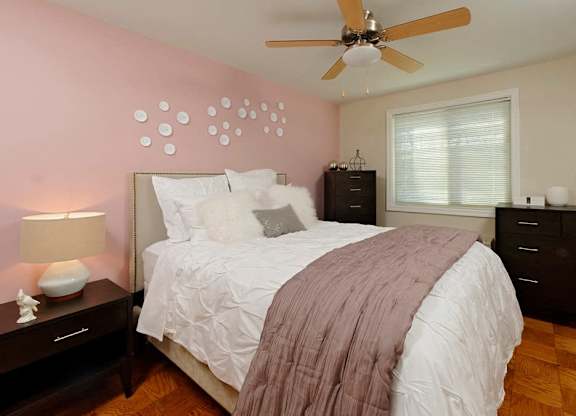 A bedroom with a bed, nightstand, and a ceiling fan.