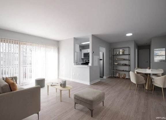 A modern living room with a grey couch, a coffee table, and a dining table set up.