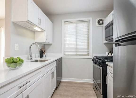A kitchen with white cabinets and a stainless steel refrigerator.