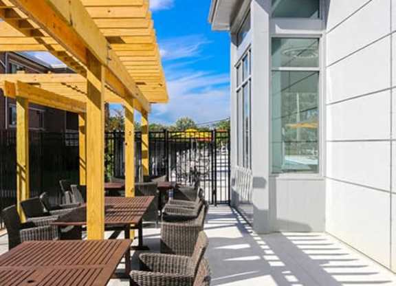 A sunny day at a modern outdoor seating area with wooden tables and chairs.