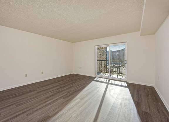 A room with wooden floors and a doorway leading to a balcony.