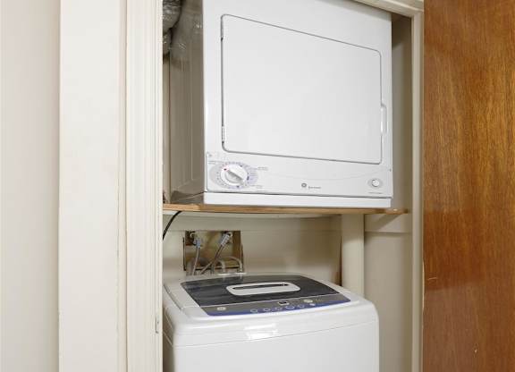 A white dishwasher is built into a cabinet under a microwave.