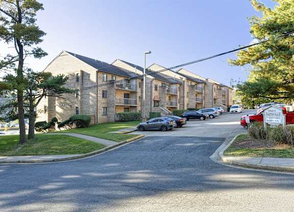 A street view of a residential area with apartment buildings and parked cars.