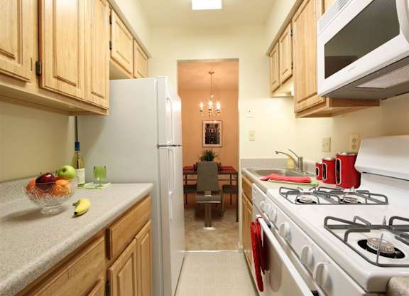 A kitchen with a white stove and wooden cabinets.