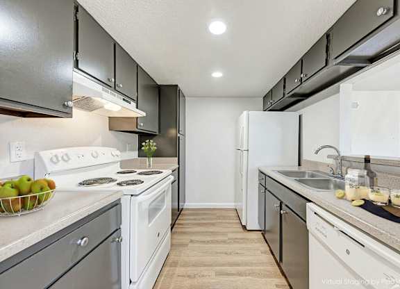 A kitchen with white appliances and a bowl of green apples on the counter.