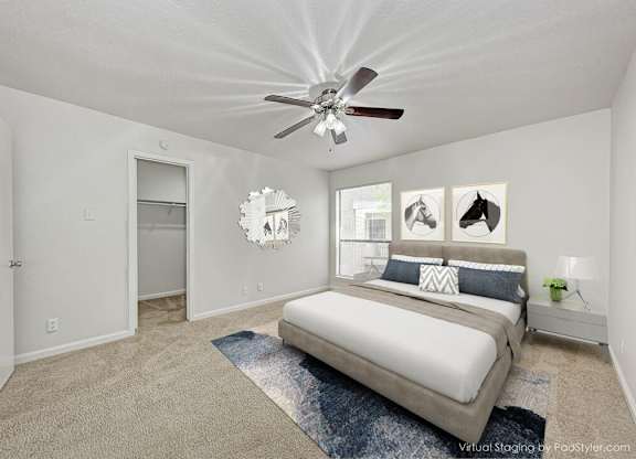 A bedroom with a bed, a ceiling fan, and pictures on the wall.