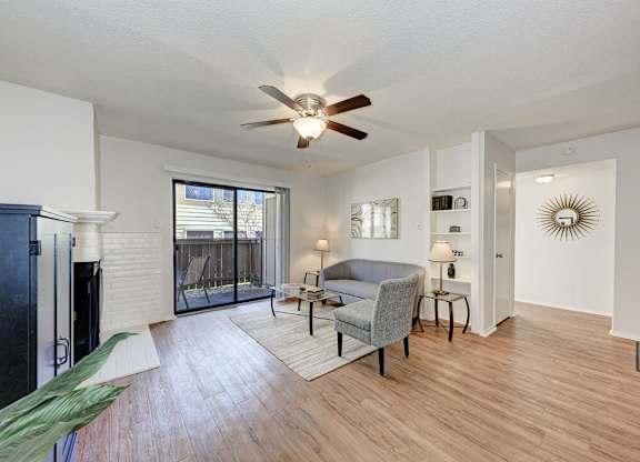 A living room with a grey couch and a ceiling fan.