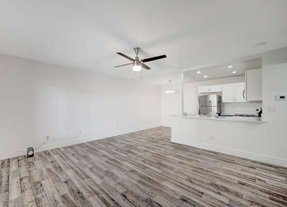 A room with a ceiling fan and wooden flooring.