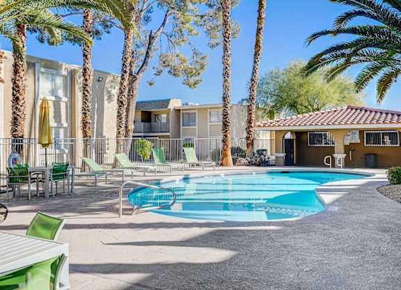 A pool surrounded by palm trees and chairs.