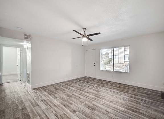 A room with a ceiling fan and a window with blinds.