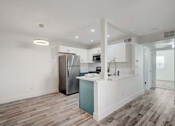 A kitchen with a refrigerator, microwave, and sink.