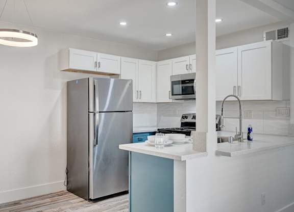 A modern kitchen with a stainless steel refrigerator and white cabinets.