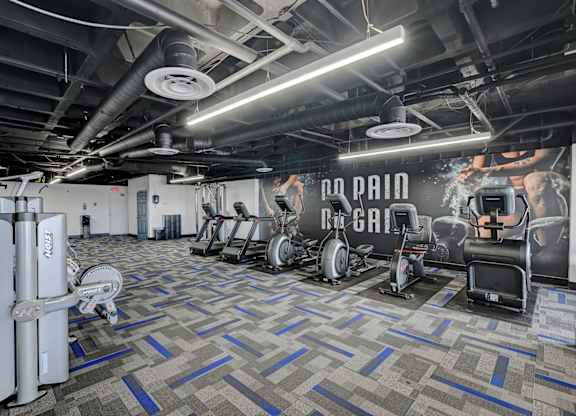 A gym with a variety of equipment including a rowing machine, a treadmill, and a weight bench.