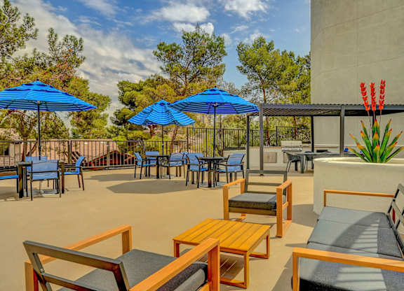 A patio with blue umbrellas and wooden furniture.