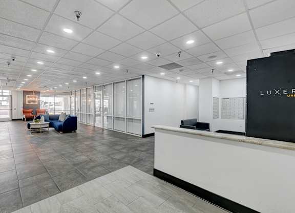 A reception area with a white reception desk and a sign that says "LUXER".