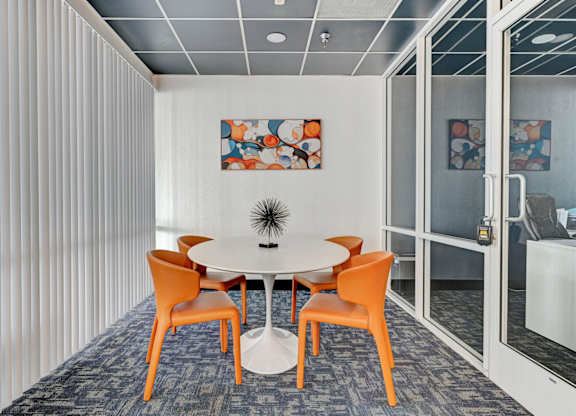 A conference room with a white table and orange chairs.
